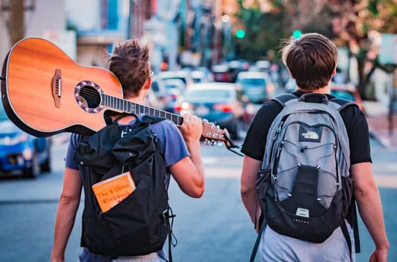 two travellers on a working holiday visa with a guitar and backpack