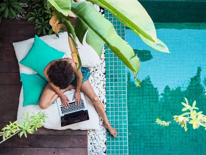 A women working remotely next to a pool