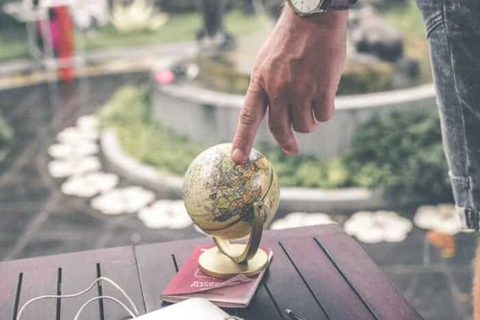 Man pointing at a globe thinking about where he can get residency.