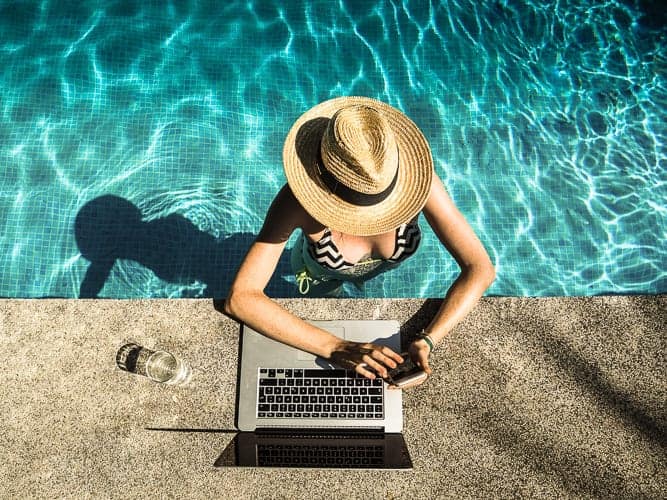 A woman in a pool sending money abroad on her smart phone.