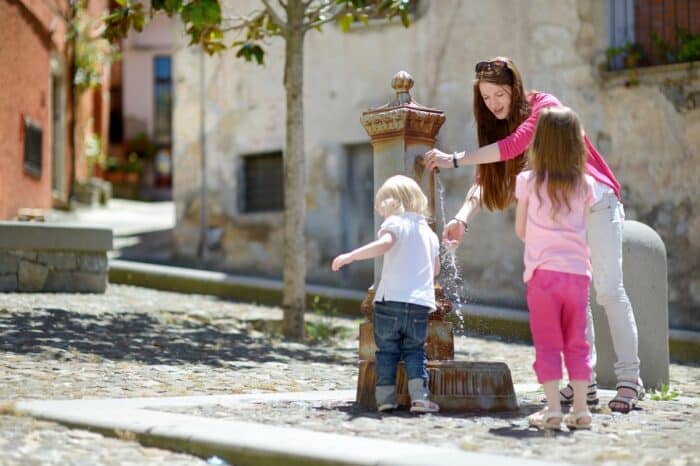 young family at public fountain in italy
