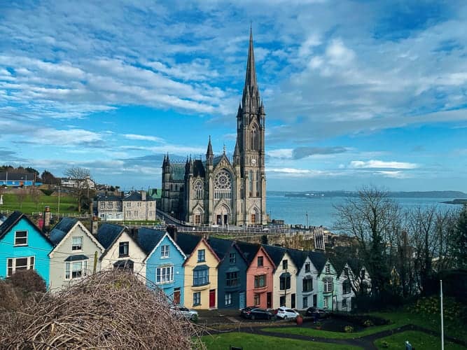 A cute village in Ireland with coloured houses and a church in the background.