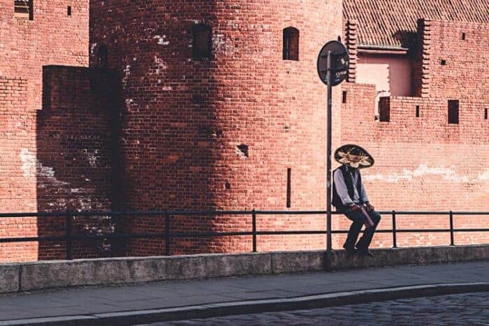 A man in a Mexican hat in front of a beautiful building