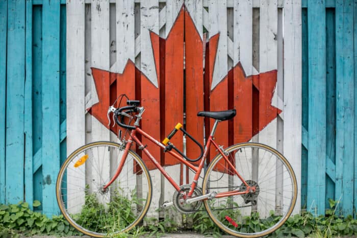 A wall decorated with the Canada maple leaf with a bicycle leaning on it.