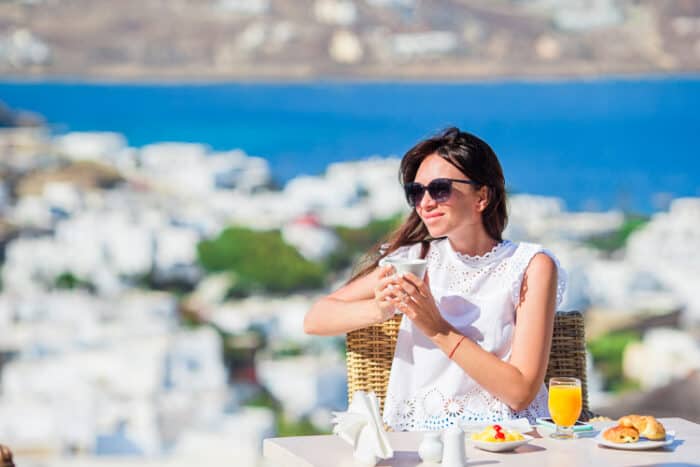 A woman having breakfast in a cafe, enjoying living in Greece