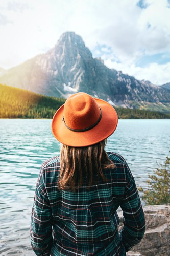 A trendy Canadian lady in an orange hat looking at the scenery at a Lake in Canada
