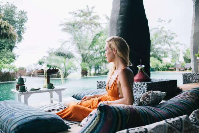 Female Crypto trader sitting next to a pool in Singapore.