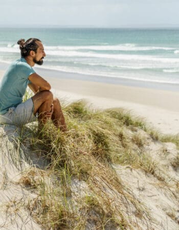 A man living in New Zealandand siting in the sand dunes