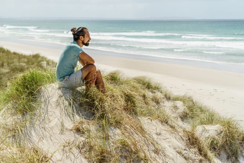 A man living in New Zealandand siting in the sand dunes
