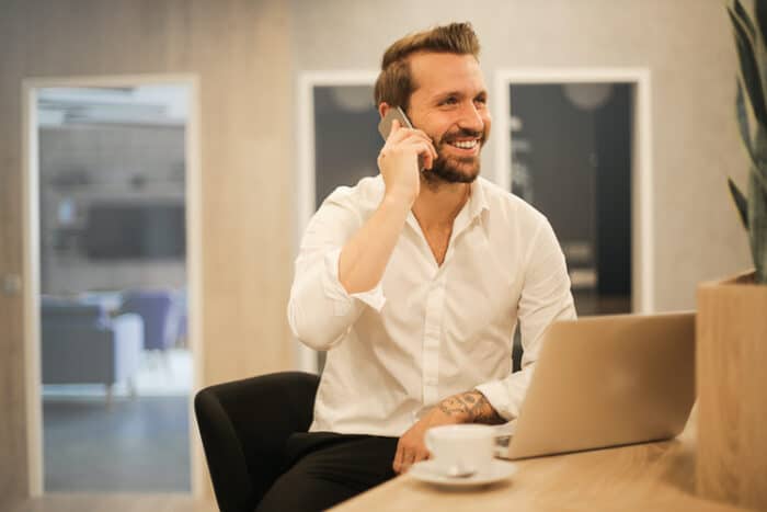 Man on the phone and laptop trading crypto