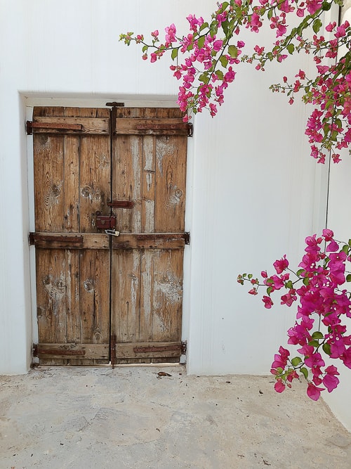 Beautiful doorway in a white building with pink flowers in a Greek town