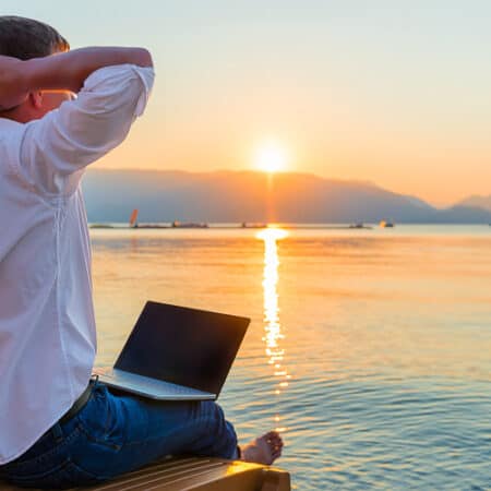 Remote worker with laptop in the morning on the beach working