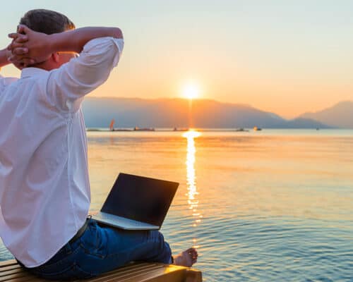 Remote worker with laptop in the morning on the beach working