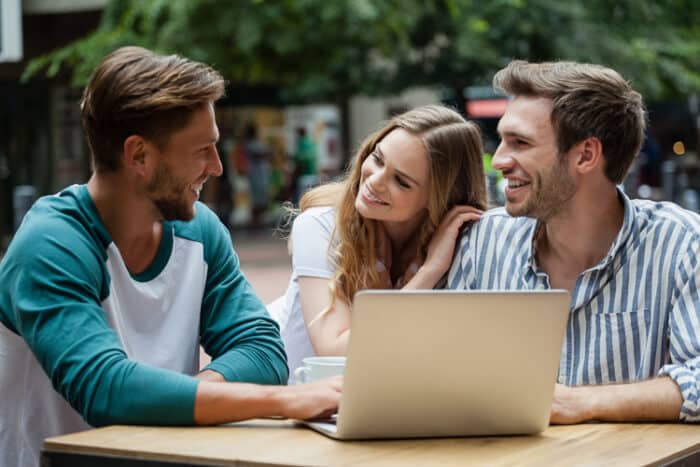 Three students discussing their studies and looking at a laptop