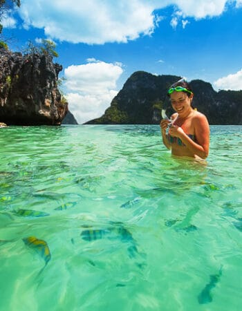 A smiling lady snorkelling in the green waters off an island in the Philllipines