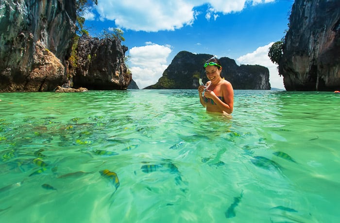 A smiling lady snorkelling in the green waters off an island in the Philllipines